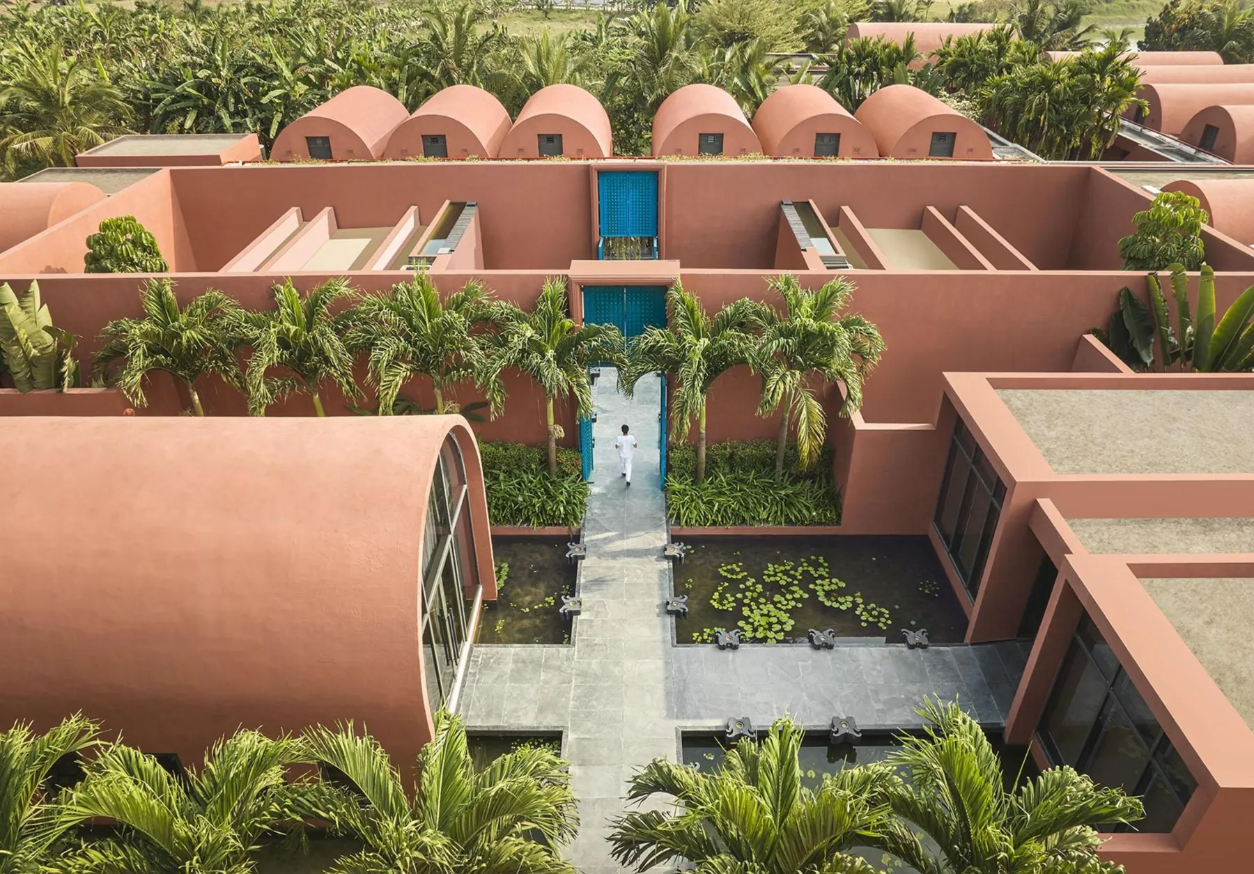 Aerial view of Devasom’s terracotta volumes, vaulted roofs and water courts