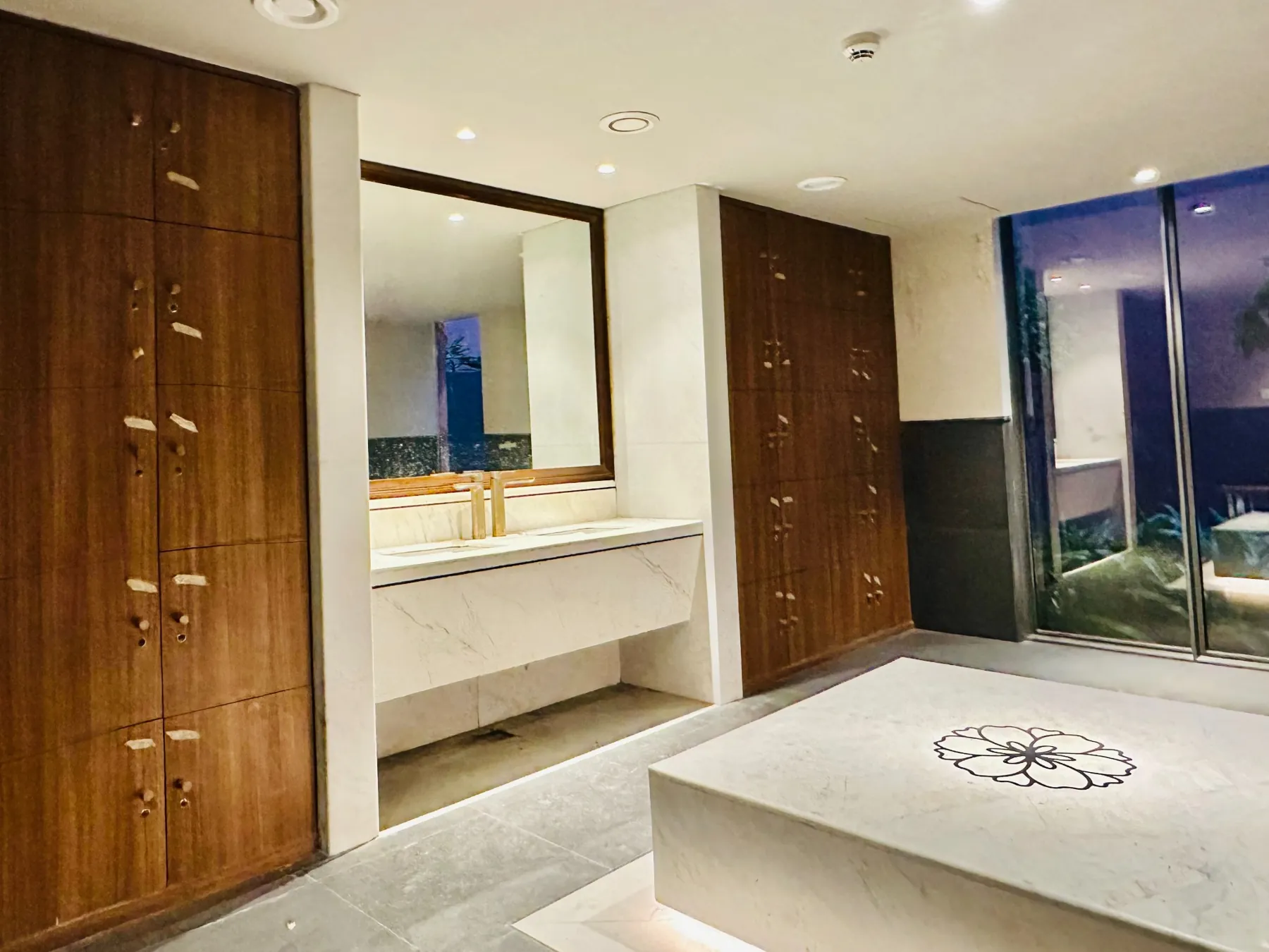 Timber lockers, a vanity and stone seating in a wellness changing room at Devasom, Kolkata