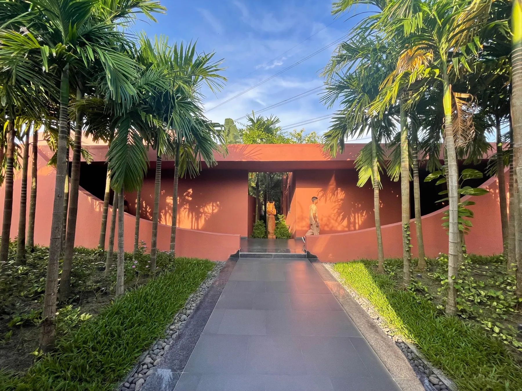 Palm-lined arrival path leading to Devasom’s terracotta entrance