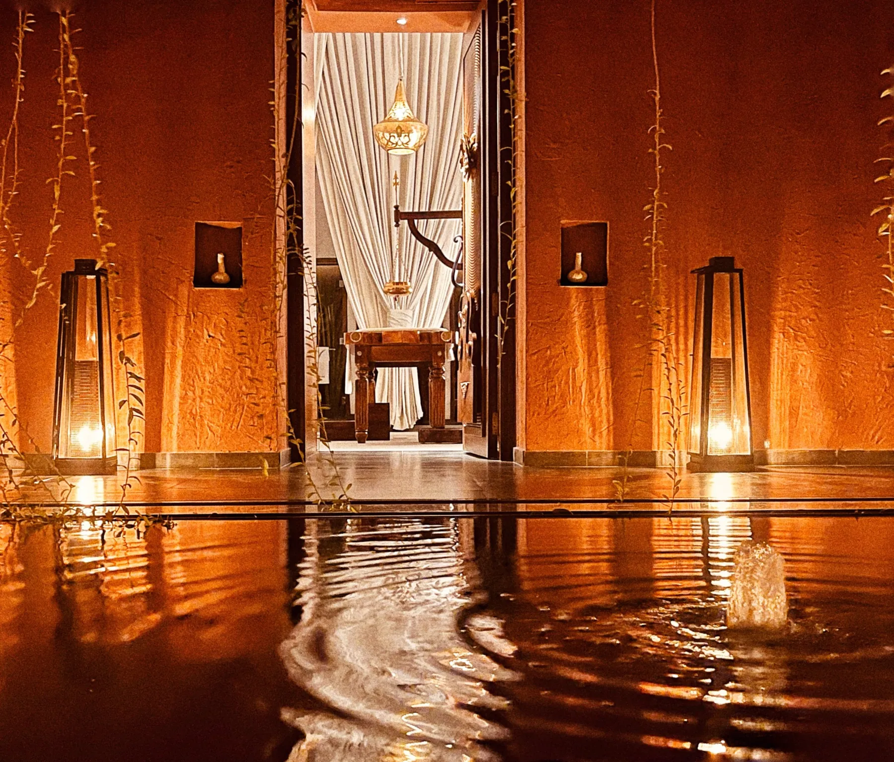 Lanterns reflected in rippling water beside the vaulted interior at Devasom
