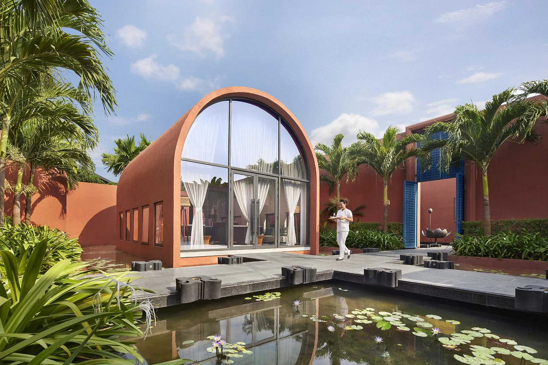 Vaulted glazed pavilion opening onto a lotus-filled water court at Devasom