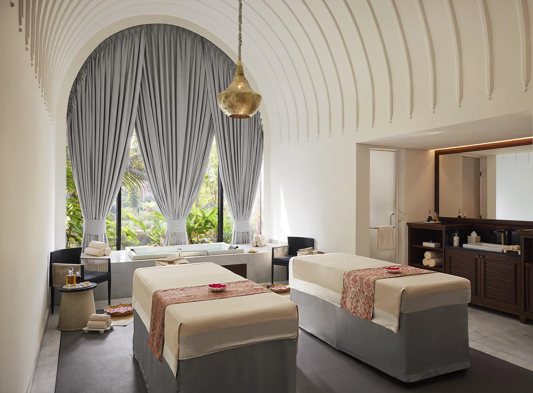 Twin treatment beds beneath a curved white ceiling at Devasom
