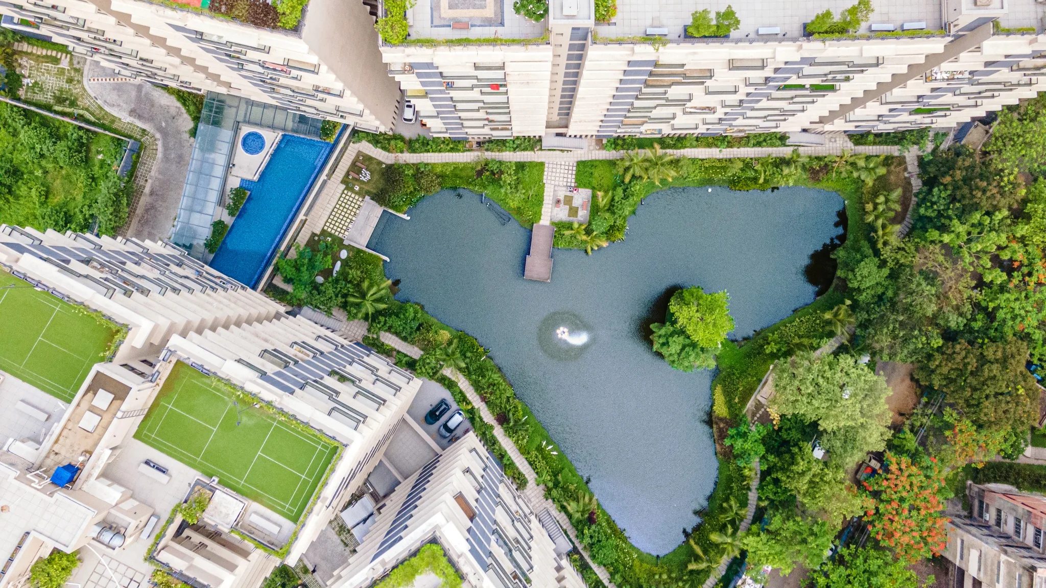 Overhead view of the preserved lake, planted island, rooftop courts and swimming pool at Jiva Homes