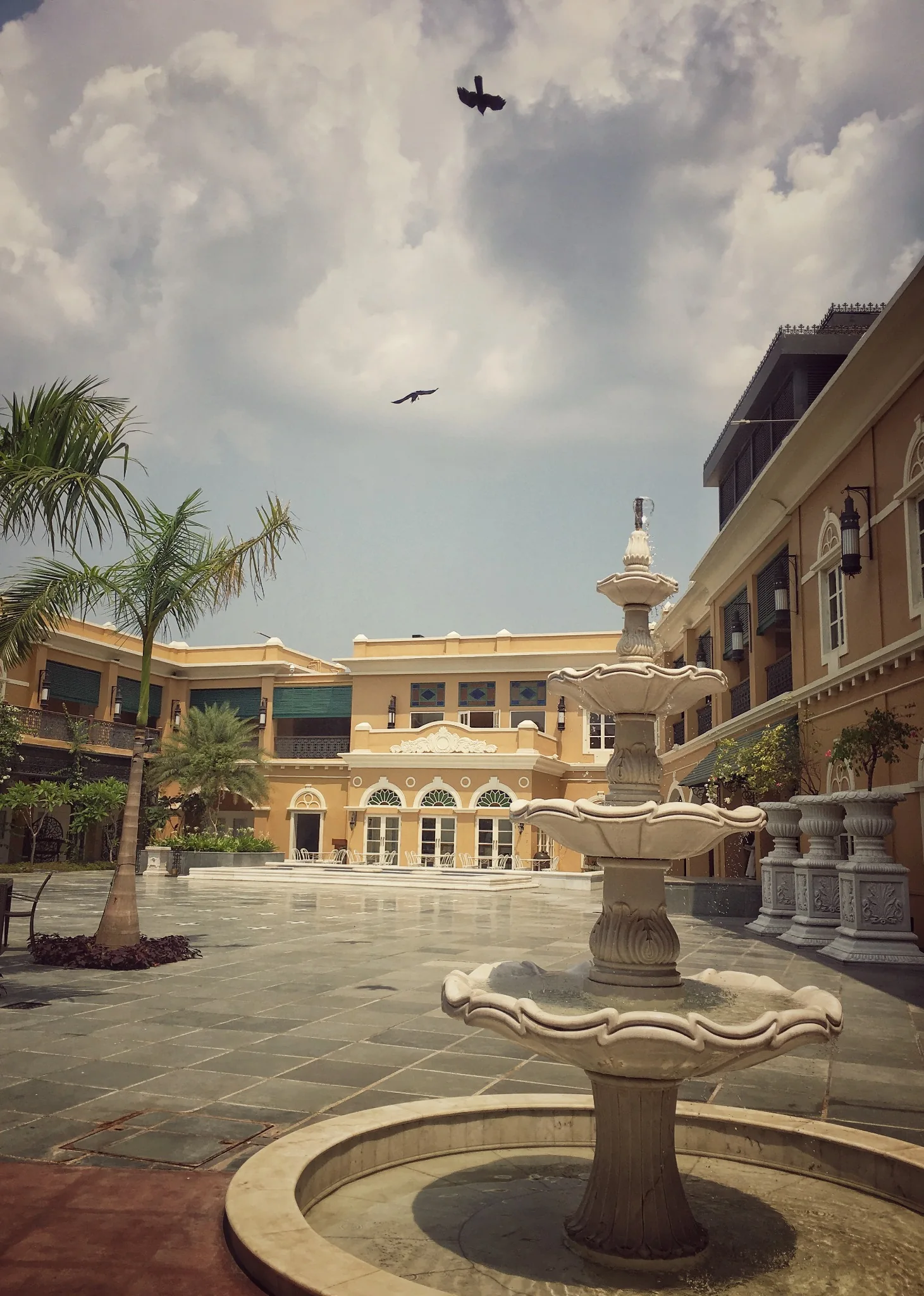 Courtyard fountain, palms and surrounding hotel facades at IHCL SeleQtions – Raajkutir, Kolkata