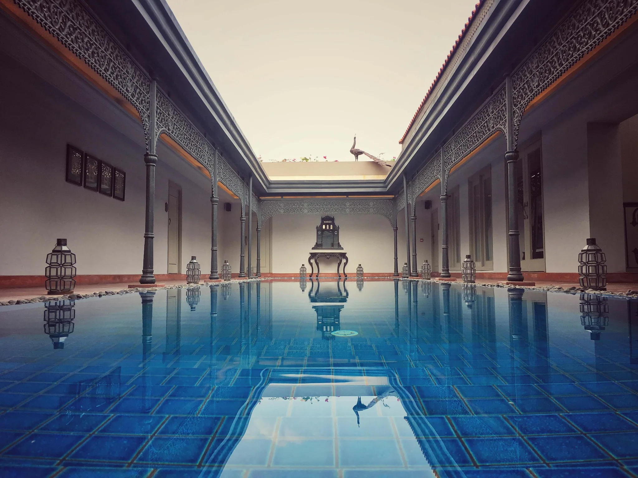 Blue swimming pool framed by verandahs and a central lantern at IHCL SeleQtions – Raajkutir, Kolkata