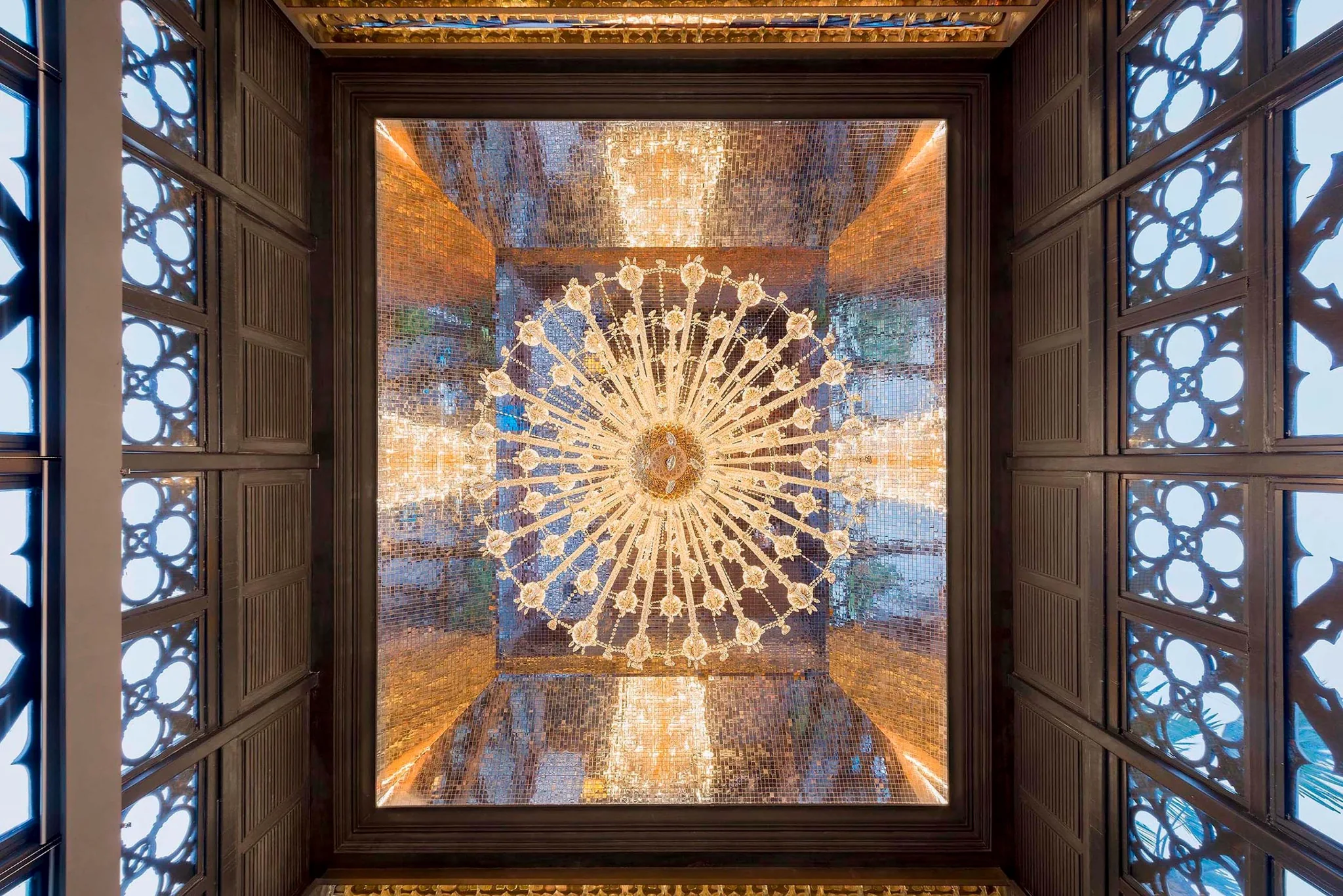 Chandelier and decorative ceiling framed by ornamental screens at Swig, Kolkata