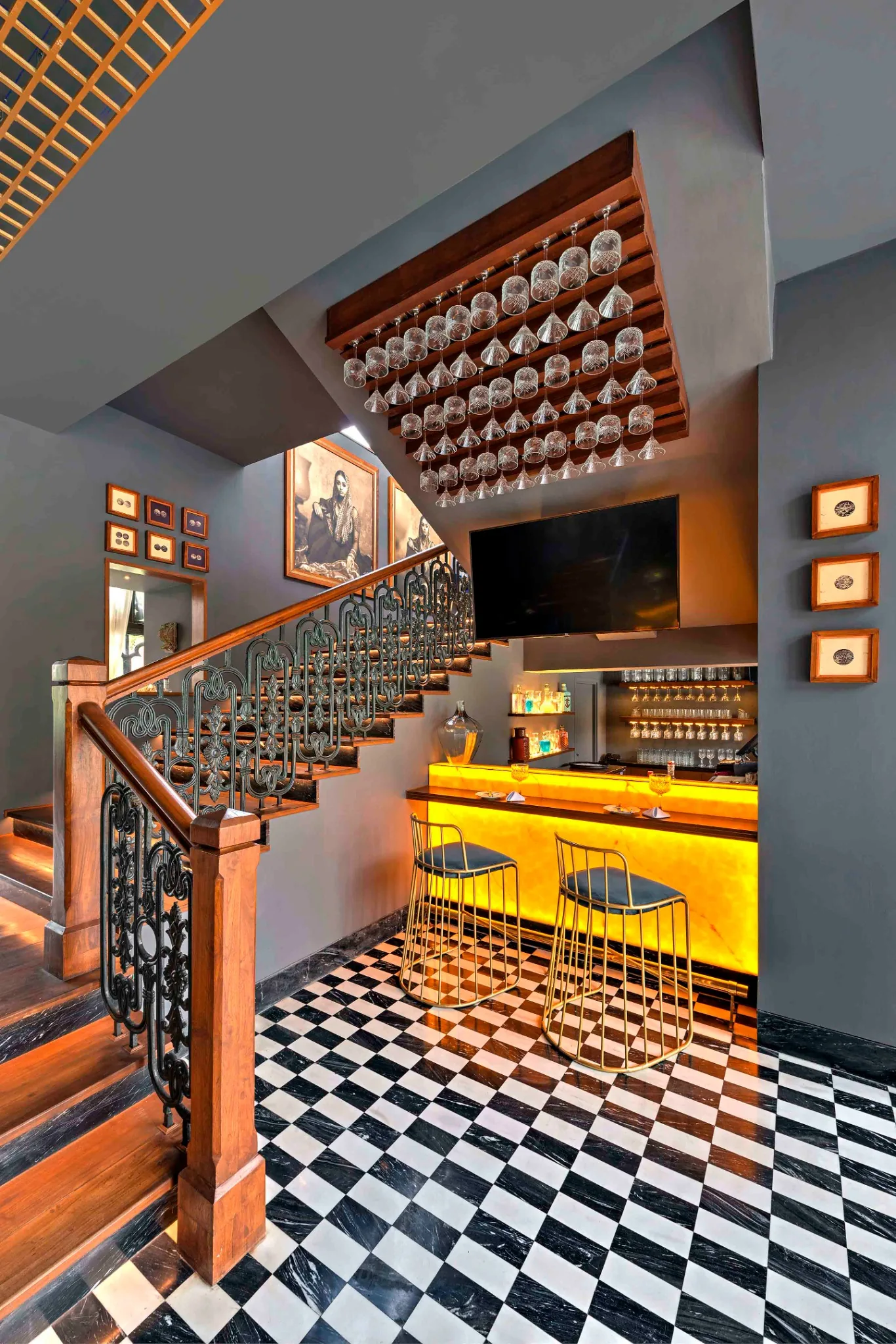 Staircase beside an illuminated bar and chequered floor at Swig, Kolkata