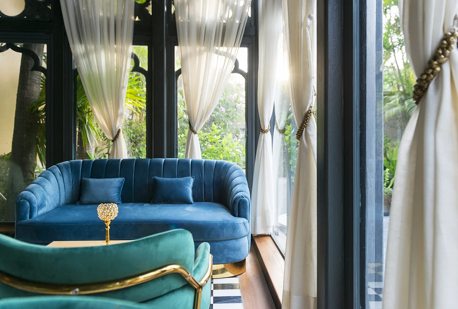 Blue and green lounge seating beside tall windows and sheer curtains at Swig, Kolkata